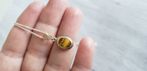 Vintage small oval tiger eye sterling silver  pendant on 18" 925 silver chain, Gray Barn Eclectic Finds online vintage store,  close up of front of pendant with striped stone in yellow, gold and brown hues.