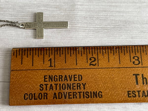 vintage silver cross lengthwise next to a wooden ruler, showing length as approximately 1.25 inches