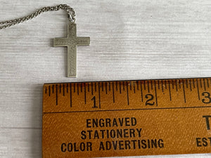 antique silver cross shown width-wise next to a wooden ruler to show the width as about .75 inches
